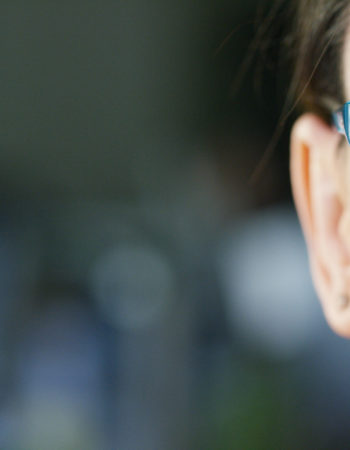 Portrait of a beautiful girl with glasses, with green eyes, shot close-up, on a blurred background. Concept: beautiful eyes, beautiful smile, vision, perfect skin.